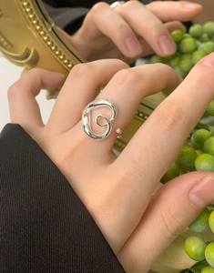Macro shot of silver hollow heart spiral ring on finger with artistic background