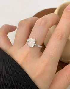 Detailed view of an oval pink crystal ring with vintage beaded silver settings on a finger