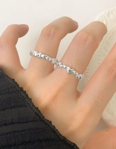 Detail of S925 sterling silver heart ring with multiple small hearts on a finger