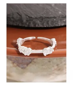 Detail of S925 sterling silver floral ring on ceramic plate with natural rock textures