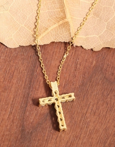 Détail du collier croix en argent S925 doré avec zircone sertie sur fond de bois