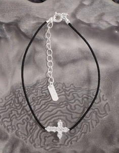 Macro shot of S925 silver clasp and cross charm on a black braided cord bracelet