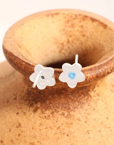 Detailansicht von Blumenohrsteckern aus 925 Silber mit blauem Zirkon auf Keramik