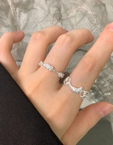 Detailed view of S925 silver croissant ring and flower cluster ring on finger