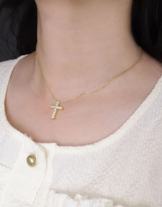 Gros plan d'un collier croix en argent S925 plaqué or avec zircons sur un mannequin