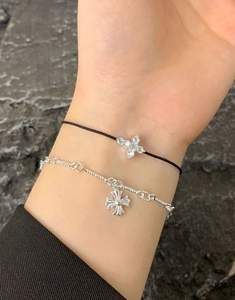 Close-up of stacked S925 silver cross bracelets with zircon inlay on a grey rock background