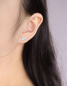 Nahaufnahme von S925 Silber Blumen Ohrstecker mit blauem Zirkon am Ohr des Modells