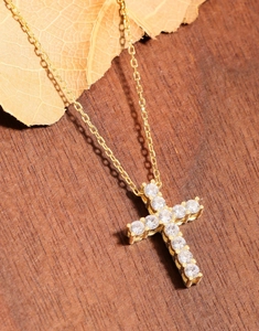 Vue détaillée du pendentif croix dorée avec zircons sur un fond en bois rustique