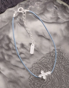 Macro shot of S925 sterling silver tag and blue woven rope with zircon butterfly pendant