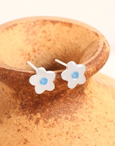 Nahaufnahme der Silber-Blumenohrringe mit blauem Zirkon auf einer Keramik-Vase