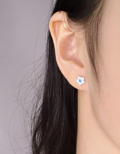 Nahaufnahme von S925 Silber Blumensteckern mit blauem Zirkon am Ohr getragen