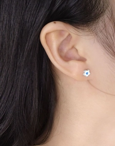 Nahaufnahme eines S925 Silber Blumenohrsteckers mit blauem Zirkon an einer Frau