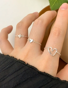 Detail showing three S925 sterling silver chain rings with heart and cross charms on a finger