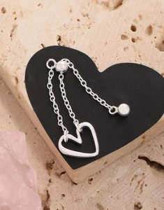 Detail of adjustable S925 sterling silver heart ring with dangling chain and polished finish
