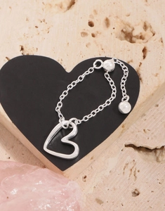 Macro shot of silver heart charm chain ring with adjustable slide clasp on stone background