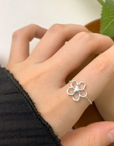 Dettaglio dell'anello a catena in argento con ciondolo a fiore e cuore sulla mano