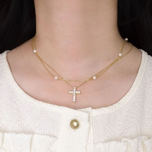 Collier double couche doré avec pendentif croix en zircon et perles porté par un mannequin