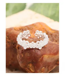 Detailed close-up of S925 sterling silver lace flower ring with zircon on red rock