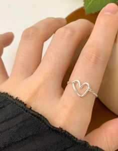 Detailed view of an adjustable heart chain ring in silver on a hand with minimalist style
