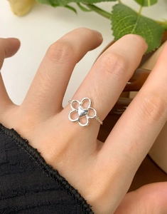 Dettaglio dell'anello a catena regolabile in argento con fiore e cuore sul dito