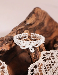 Macro d'une bague nœud en argent S925 avec dentelle vintage sur un support en bois sombre