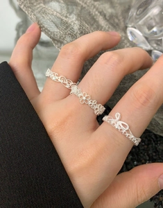 Detailed view of two S925 sterling silver lace flower rings with bow design on hand