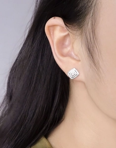 Close-up of geometric square S925 silver stud earrings with zircon worn on an earlobe