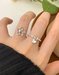 Dettaglio di anelli in argento sterling S925 con fiori e ciondolo a cuore indossati