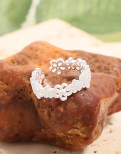 Detailed view of hollow lace flower silver ring resting on a reddish mineral stone