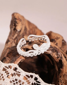 Vue macro d'une bague en argent avec nœud scintillant et anneau ondulé délicat