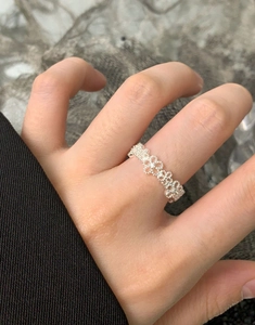 Detailed view of silver lace flower ring with hollow clover patterns on finger