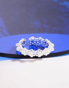 Macro shot of silver lace flower ring with pearl accents on a blue decorative tray