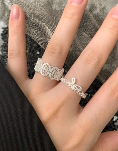 Gros plan sur un ensemble de bagues en argent avec dentelle et nœud au design ajouré