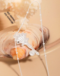 Detail of S925 sterling silver shell key pendant on a beaded chain with coral background