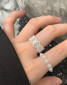 Detailed close-up of lace-style silver rings with pearls on hand in a vintage setting
