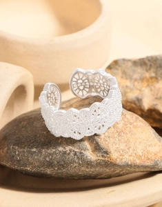 Macro shot of silver lace hollow flower ring on stone showing intricate metal texture