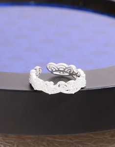 Detailed close-up of intricate lace crown hollow scrollwork on a silver adjustable ring