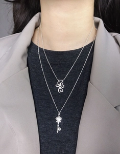Detail of layered S925 silver necklaces with hollow clover and vintage key pendants