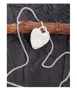 Detailed close-up of S925 sterling silver heart pendant with floral shell texture on wood