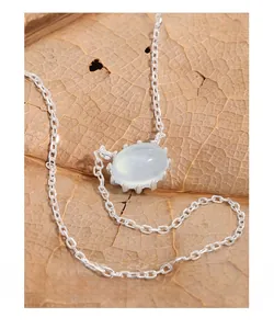 Macro shot of oval light blue gemstone pendant on S925 silver chain with autumn leaf detail