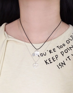 Close-up of layered S925 silver heart necklaces on black cord and silver chain