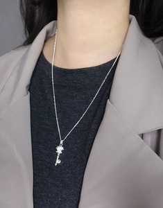 Detail of silver S925 shell key necklace worn on model with elegant grey suit