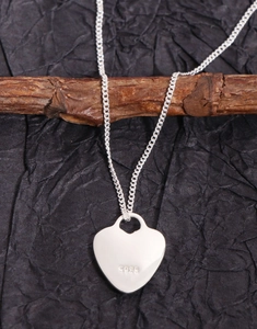 Macro shot of S925 sterling silver heart pendant showing fine texture and hallmark