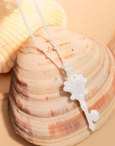 Close-up of S925 sterling silver shell key pendant necklace on a natural seashell