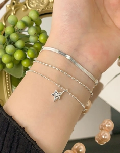 Dettaglio del set di braccialetti a stella in argento S925 indossati al polso con ciondoli