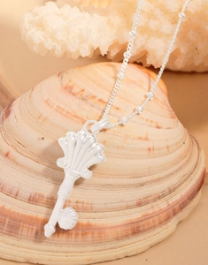 Macro shot of silver key pendant with shell details on a decorative sea shell background