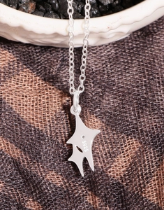 Detail of S925 sterling silver necklace with geometric pendant on a white ceramic bowl