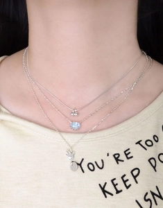 Macro detail of triple-layer S925 silver necklace with aquamarine stone and cherry charm