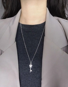 Detail of S925 sterling silver key necklace worn by a model in casual business attire