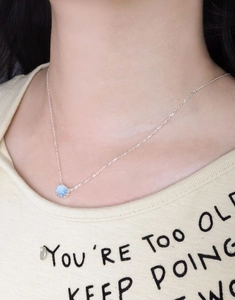 Detail of S925 sterling silver necklace with oval sky blue aquamarine on model